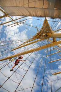 A passenger climbs up the rigging to the crows nest